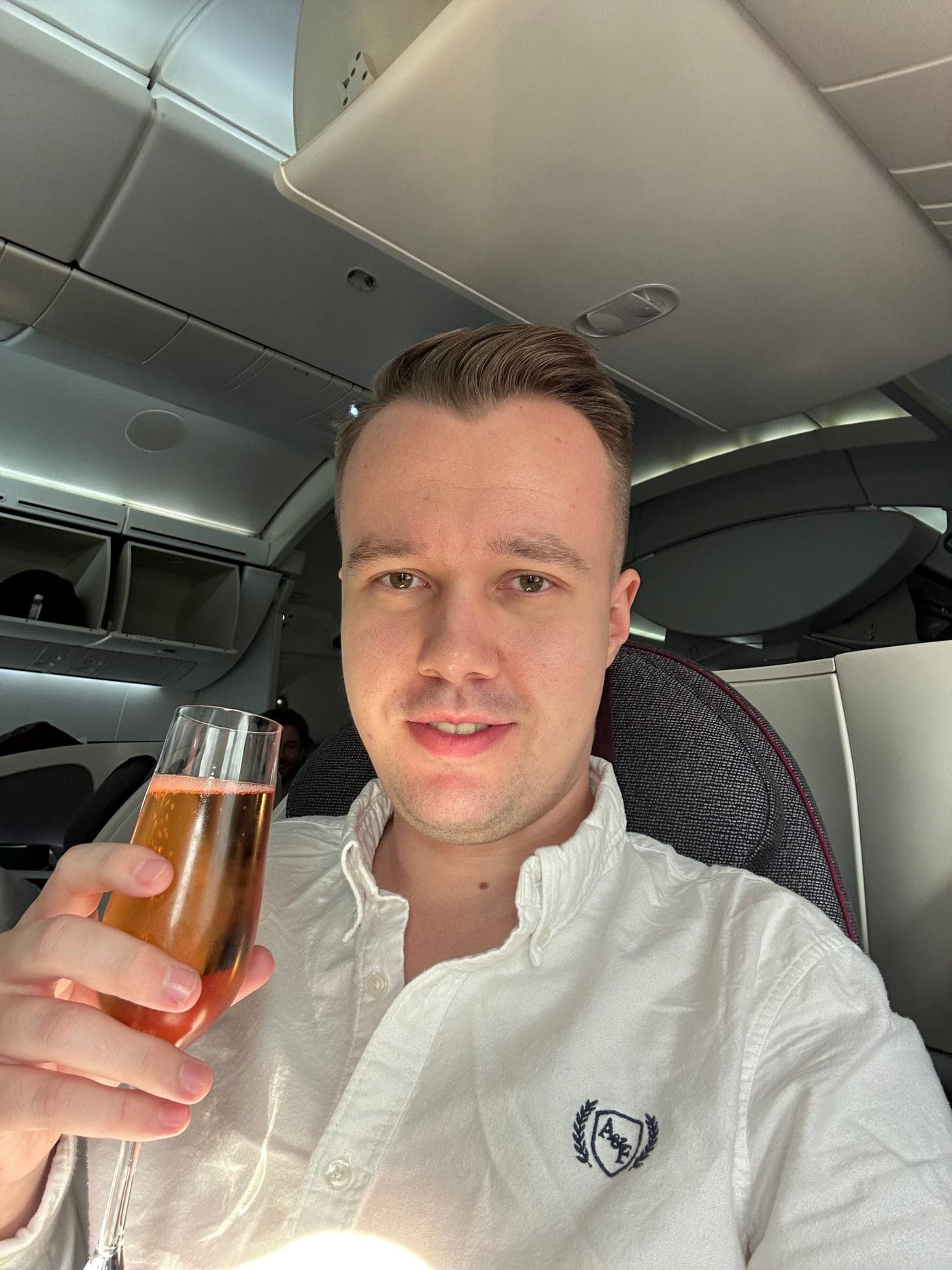 Jendrik mit einem Glas Champagner am Fensterplatz in der Business Class