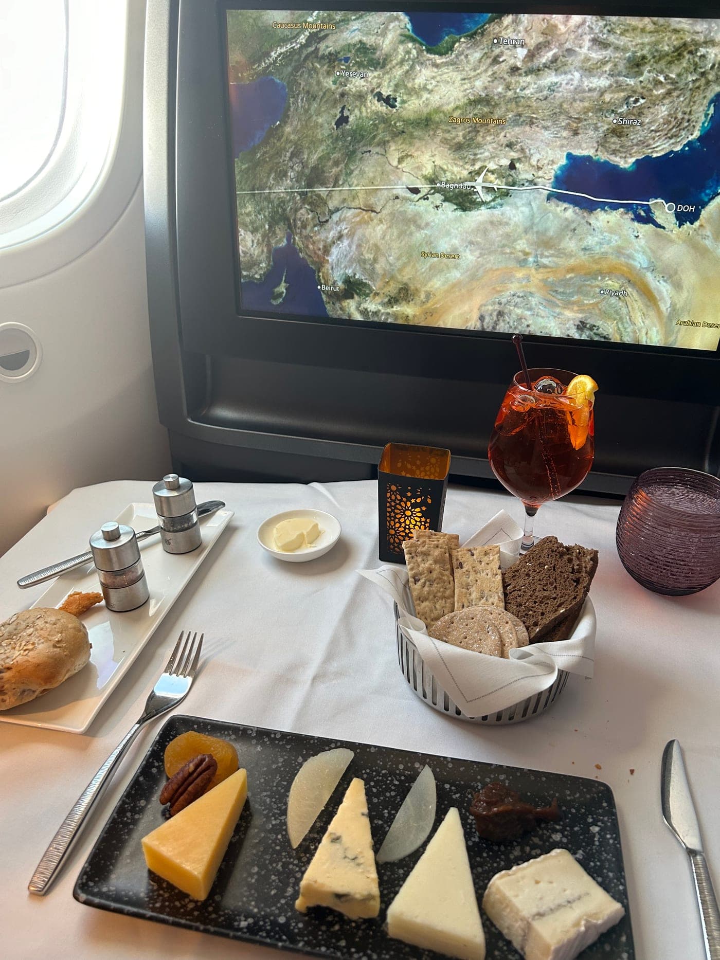 Käseplatte und Brotkorb am Platz, auf dem Bildschirm nähert sich die Maschine über Bagdad dem Ziel Doha