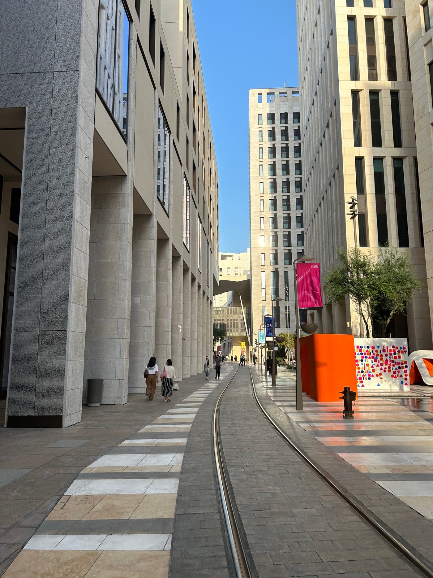 Fußgängerachse mit Tramgleisen zwischen hellen Neubauten im Stadtteil Msheireb in Doha